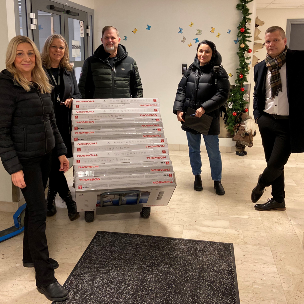 Överlämning av tv-apparater i en korridor på sjukhuset. Bidragsgivare syns på bild.